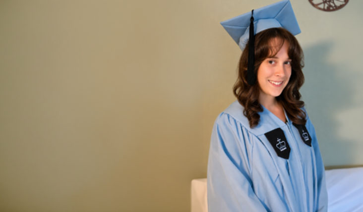 Hannah smiles for a photo, dressed in the Columbia cap and gown.