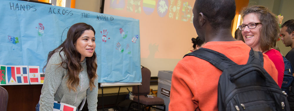 International student behind table at a career fair talking to other students across the table. 