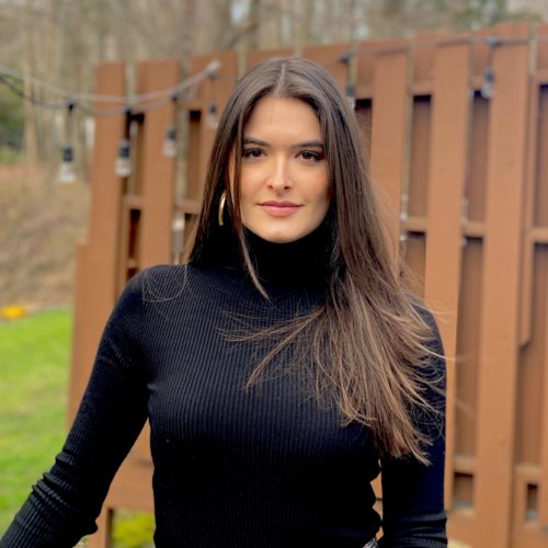 Elisa Masiero wearing a black turtleneck sweater, has long brown hair