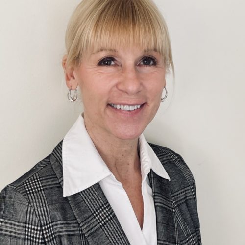 Nancy Kaari Brookdale's VP Advancement. Blond hair with bangs, styled up. She is wearing a white blouse and a gray blazer. Smiling.