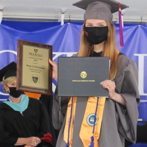 Nora Thompson holding up her award and diploma at graduation