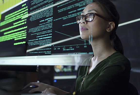 photo of a young woman looking at see through data whilst seated in a dark office