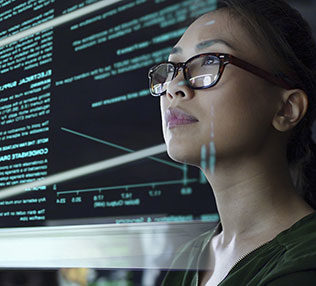 photo of a young woman looking at see through data whilst seated in a dark office