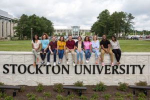 group of students sitting on the Stockton University wall