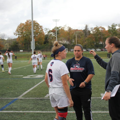 Head coach and assistant coach talking to women's soccer player