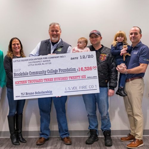 Six adults, 4 men and 2 women and two children in their arms present a large sized check