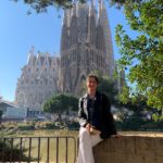 ragazza in Spagna durante un programma di studio all'estero, seduta su un muro con una cattedrale dietro di lei.