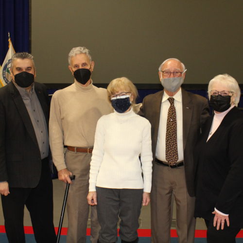 three men and two women all wearing masks dressed casually nice