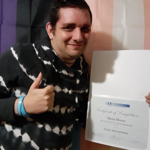 Man wearing a navy shirt and white stripes. Has his thumb up holding a certificate.