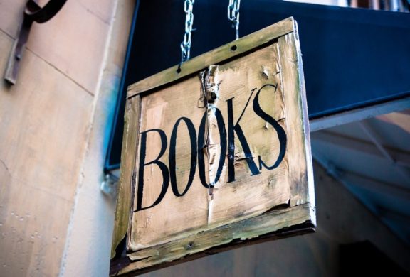 a book sign hanging by chains on the side of a building