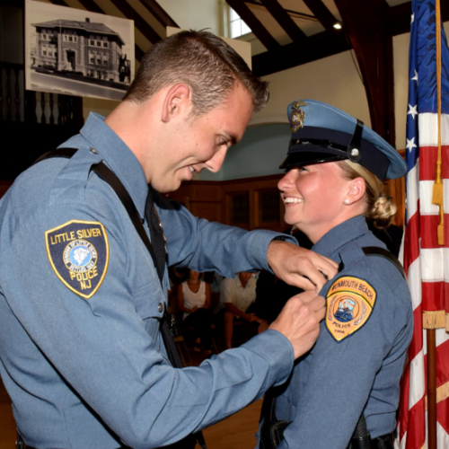 Male police officer from Little Silver pinning Amy Beringer of the Monmouth Beach Police Department