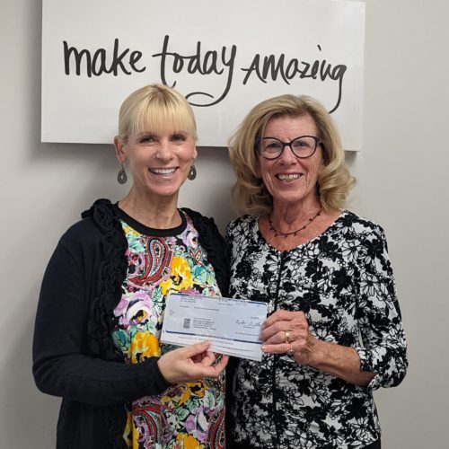 Two women smiling and holding a check