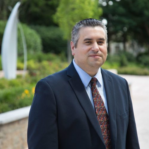 Man wearing a navy suit and dark red tie.