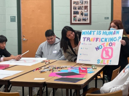 A male and female student making signs and showing one finished.