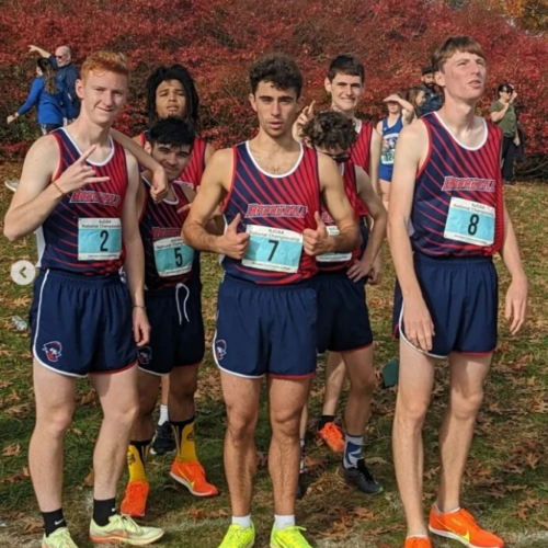 5 men's cross country teammates in their red and blue tops and shorts and sneakers giving a thumbs up.
