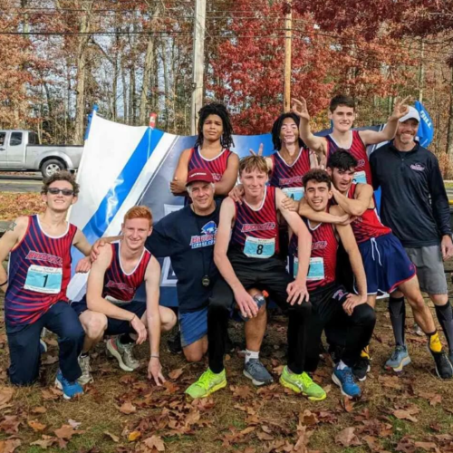 8 cross country male runners in wearing red and blue tank shirts and two coaches in a group photo.