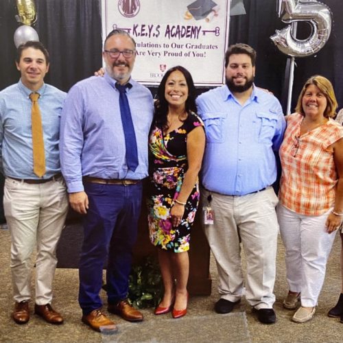 Eight men and women dressed nicely and smiling.