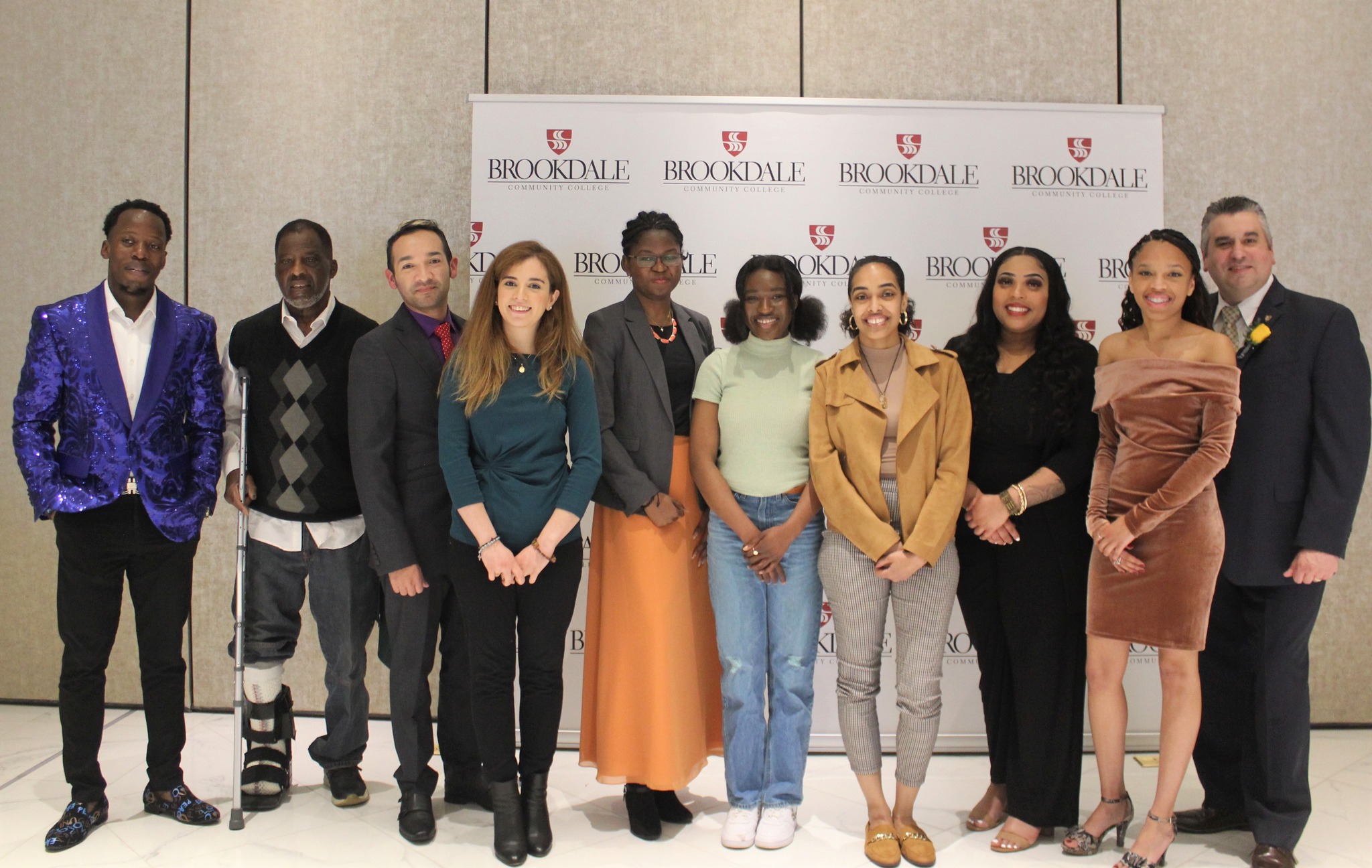 Group of students standing in front of a Brookdale logo repeat . All dressed nicely.