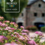 Cover of report that has the student center in the background and pink flowers in the foreground.