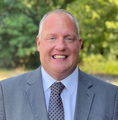 Man wearing a big smile and a gray suit and tie.