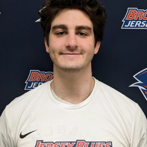 Man with dark hair and smiling wearing a Jersey Blue tennis shirt.