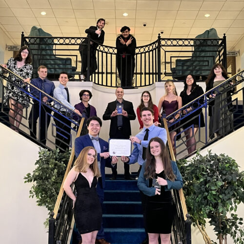 Group of college students all dressed up standing on a large staircase.
