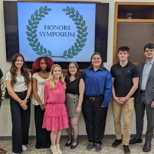 Eight students in front of Honors Symposium sign.