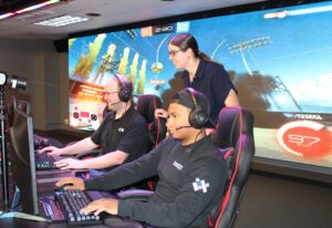 Three gamers playing in front of a large screen.