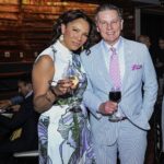 A man in a suit and tie and a women wearing a dress with wine glasses in their hands.