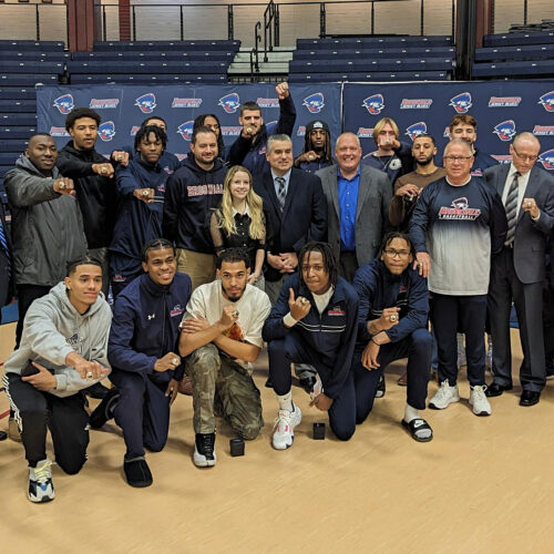 Group of students, alumni, coaches, president, trustees celebrating the rings of the national championship team. Group photo.
