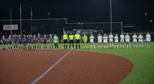 Two women's teams on the soccer field before the game. Lined up on either side of the refs.