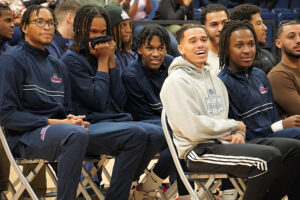 Bunch of men's basketball players in their seats smiling at their ring ceremony.