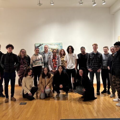 A group of students and faculty in the CVA Gallery where Karen Bright's exhibition Within The Anthropocene is in the background.
