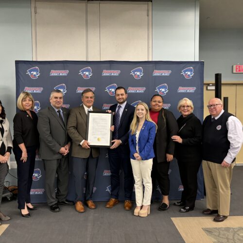 Group of adults with two men in the center holding a proclamation for Trustee Vice Chair Bret Kaufmann.