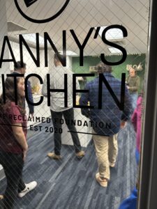 Looking into the kitchen from the window pane by the door. SIgnage over the window says Danny's Kitchen.