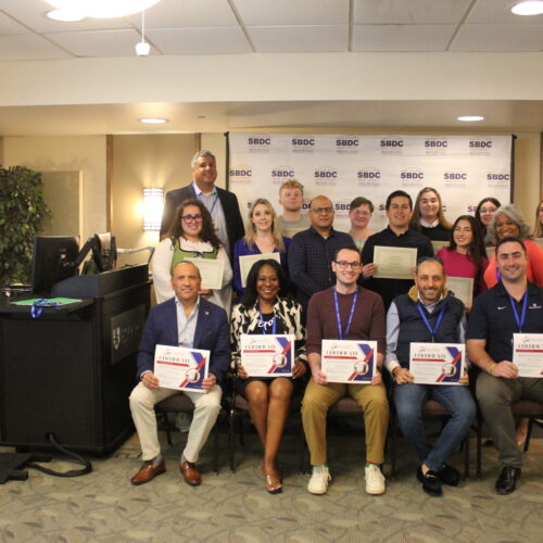 Group of men and women standing and sitting holding their certificates of participation.