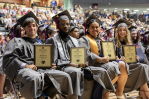 Four graduates showing their outstanding student awards.