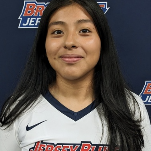 Woman with long black hair, wearing Jersey Blues Volleyball jersey.