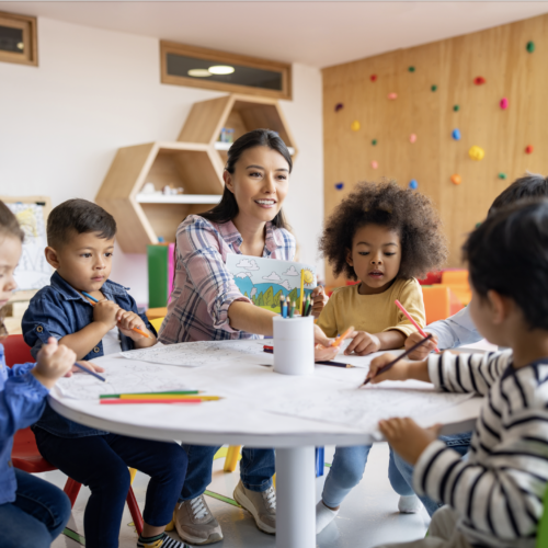 PreK-3 Teacher at table with five students.
