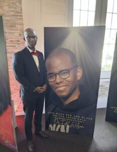 Fidel Wilson standing in front of poster that his image on it.
