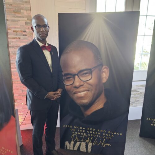 Fidel Wilson standing in front of poster that his image on it.