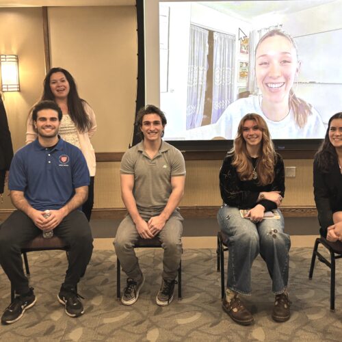 Five NASA Interns sitting on chairs and one on the screen.