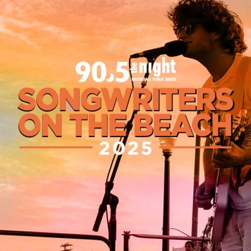 songwriters on the beach 25. Man playing guitar with sunset in the background.