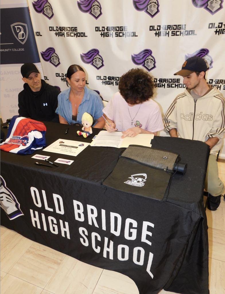 Evan Kraja signs his letter of intent as his dad, mom, and brother look on.
