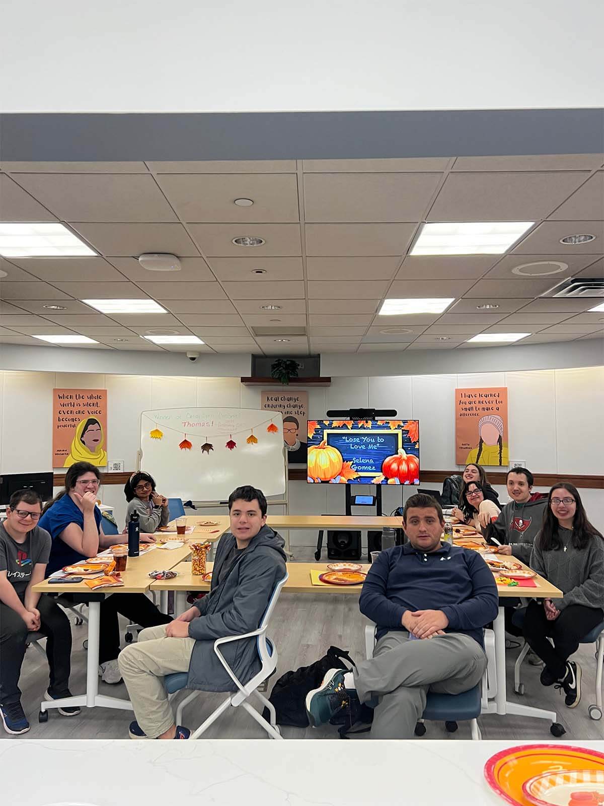 Students pose for a photo while seated around a table and enjoying a meal.